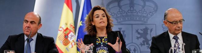El ministro de Economía y Competitividad, Luis de Guindos; la vicepresidenta del Gobierno, Soraya Sáenz de Santamaría, y el ministro de Hacienda, Cristóbal Montoro, el viernes tras aprobar el Consejo de Ministros los recortes.