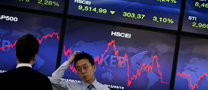 Corredores de bolsa conversan junto a una pantalla que muestra información bursátil en Seúl (Corea del Sur).