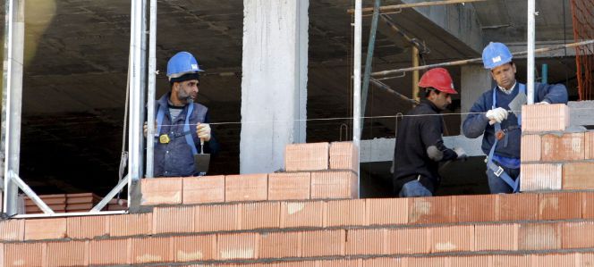 Tres obreros trabajan en la construcción de una vivienda.