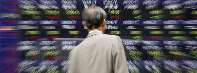 Un empresario observa un panel electrónico exhibido en un edificio de Tokio (Japón) que muestra varios valores bursátiles de la sesión de la Bolsa de Tokio.