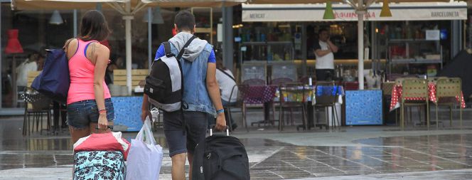 Unos turistas caminan con sus maletas por el barrio de La Barceloneta.