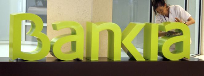 Una operaria limpia el logo de Bankia.
