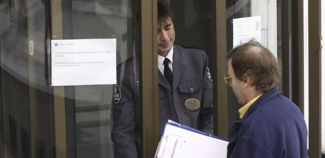 Una persona pregunta a un agente de seguridad en la sede del Banco Madrid, entidad intervenida por Banco de España y la CNMV, y filial de Banca Privada d'Andorra (BPA).