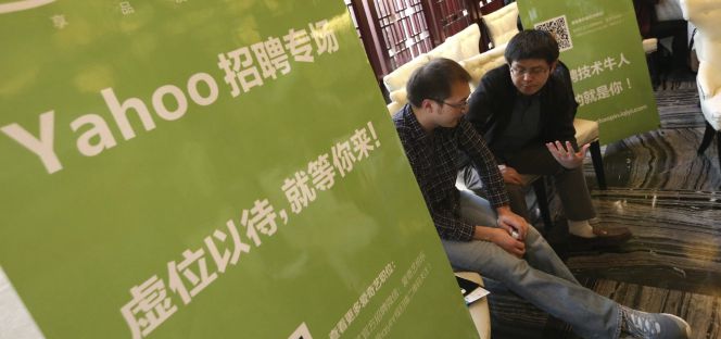 Un exempleado de la oficina de Yahoo conversa con un trabajador de recursos humanos de otra compañía durante una feria especial de oportunidades laborales para extrabajadores de Yahoo en Pekín este jueves.