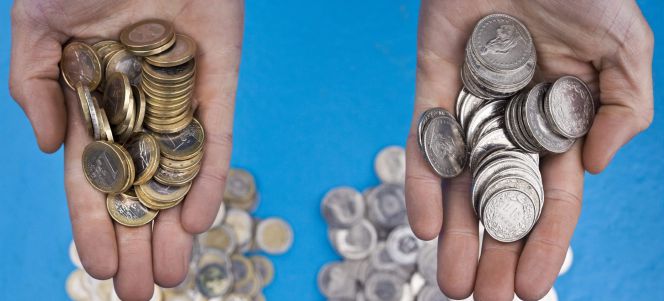 En la imagen, una persona sosteniendo en sus manos monedas de euro (izq) y monedas de franco suizo, en Zurich (Suiza).