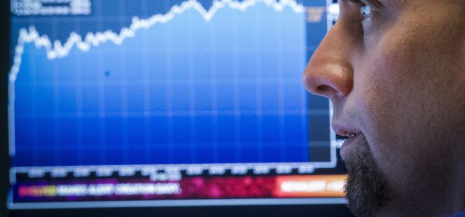 Un trader del NYSE de dudoso vello facial mira un monitor de cotizaciones.