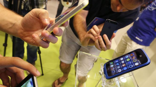 Varias personas observan un smartphone una tienda de telefonía de Madrid