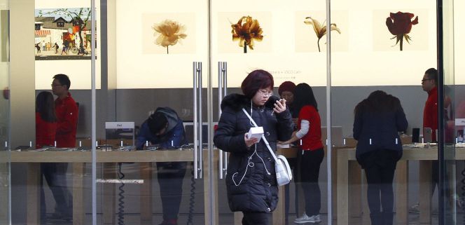 Una joven china junto a una tienda de Apple en Pekín (China).