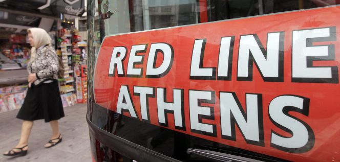Una mujer camina junto a un autobús turístico en Atenas, Grecia.