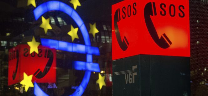 El símbolo del euro, reflejado en un cristal frente a un teléfono de emergencia en Fráncfort