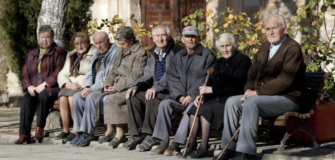 Varios ancianos toman el sol en unos bancos de Olmeda de la Cuesta, Cuenca.