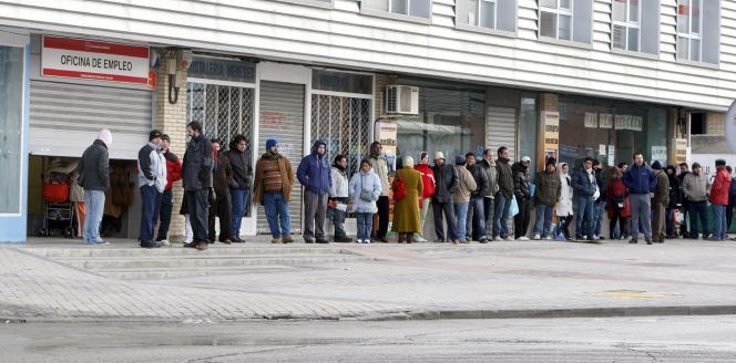 Varias personas forman una larga cola ante una oficina del INEM.