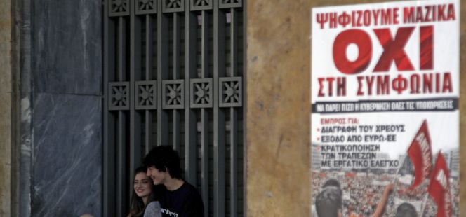 Una pareja junto a un cartel que pide el "no" en el referéndum del domingo, en Atenas