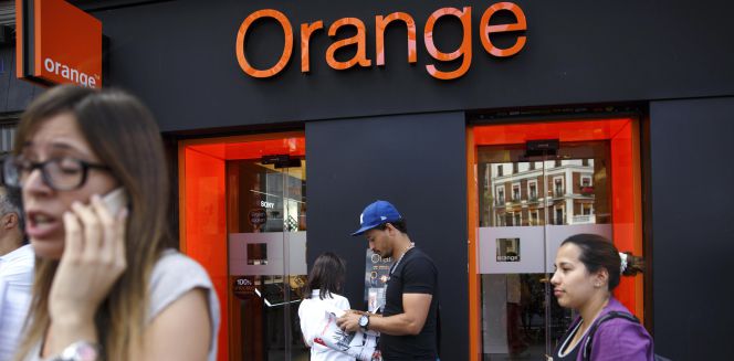 Varias personas junto a una tienda Orange en Madrid.