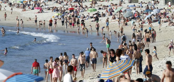 Varias personas disfrutan de las temperaturas veraniegas que han llenado de gente las playas de las Rías Bajas de Galicia. En la imagen, la playa de Samíl en la Ría de Vigo.