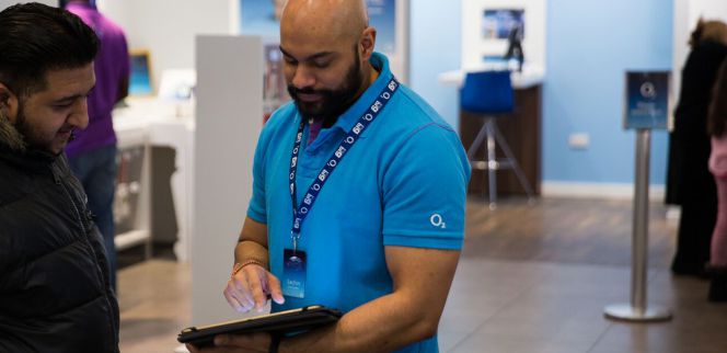 Un empleado de una tienda de O2 en Reino Unido utiliza la solución de Qudini para atender a un cliente.