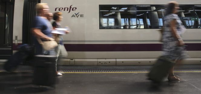 Varios viajeros esta mañana en la estación de Atocha delante de un AVE.