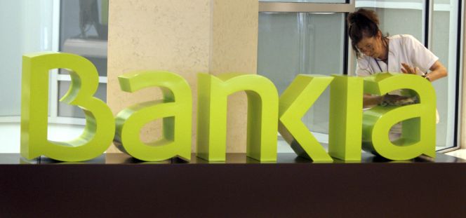 Una operaria limpia el logo de Bankia.