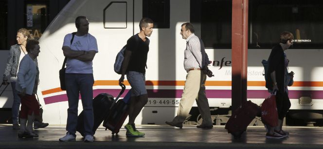 Varios pasajeros de tren con equipajes caminan por un andén de la estación de Chamartín.