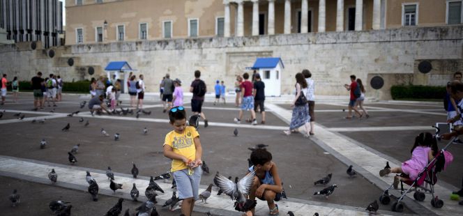 Un grupo de niños juega con las palomas frente al edificio del Parlamento griego en Atenas