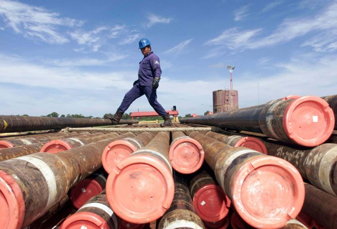 Un trabajador de Pemex cruza por encima de unos barriles de petróleo