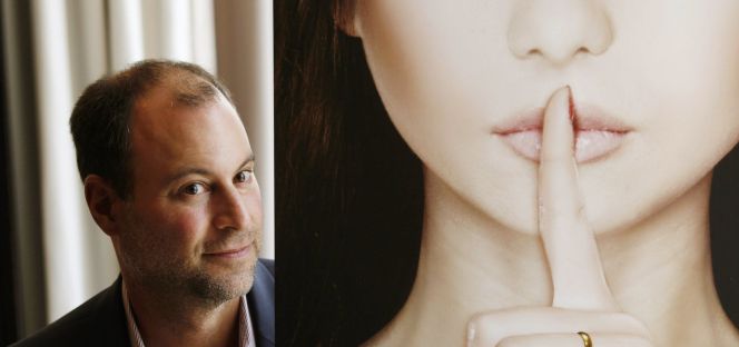 Noel Biderman, fundador de Ashley Madison, posa junto a un cartel de la web de contactos.