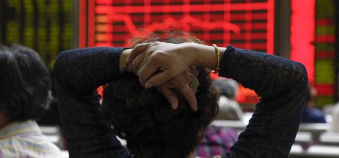 Una mujer comprueba la evolución de la bolsa de Shangái en Pekín (China)