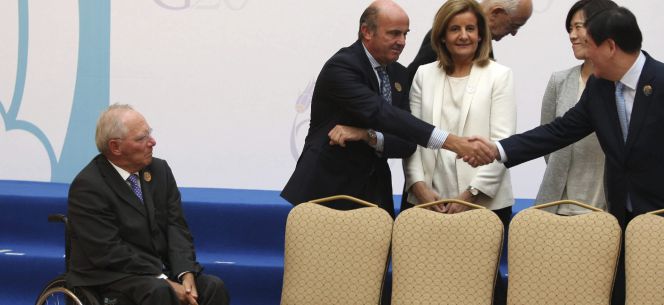 El ministro español de Economía, Luis de Guindos, saluda a su homólogo japonés, Taro Aso, ante la mirada del ministro de Finanzas alemán, Wolfgang Schäuble, y la ministra española de Empleo y Seguridad Social, Fátima Báñez. Hoy, en Ankara (Turquía), durante la cumbre de ministros de Finanzas del G20.