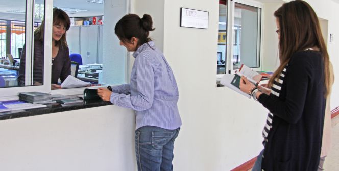 Una funcionaria atiende a estudiantes de la Universidad.