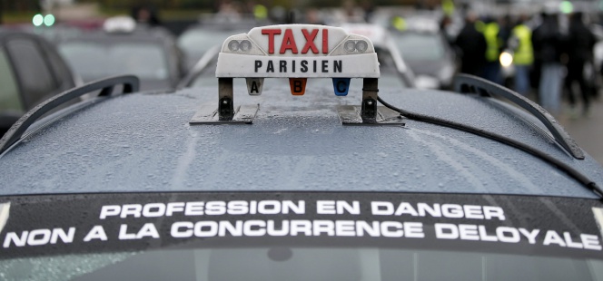 El cartel "La profesión está en peligro. No a la competencia desleal" colocado en el parabrisas de un taxi durante el paro convocado por el sector en París contra la plataforma Uber.