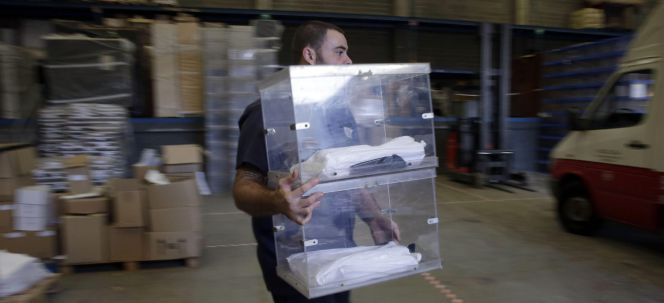 Un operario de la empresa encargada de repartir el material electoral trasnporta una urna en el almacén municipal de Barcelona.
