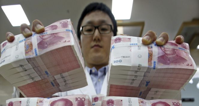 Un oficinista mueve fajos de billetes de 100 yuanes chinos a lugar seguro en la sede del Korea Exchange Bank en Seúl (Corea del Sur).