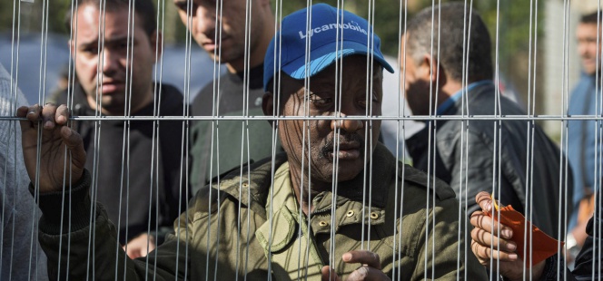 Un hombre espera para recibir ropa y calzado en un campo de refugiados construido en un parque cercano a la Oficina de Inmigración de Bruselas.