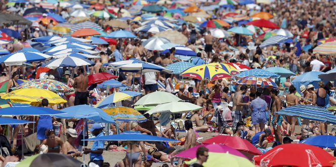 Un gran número de personas disfrutan del buen tiempo estival en la playa de la Malvarrosa, en Valencia.