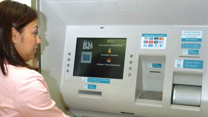 Una mujer con una chaqueta dudosa saca dinero en un cajero automático.