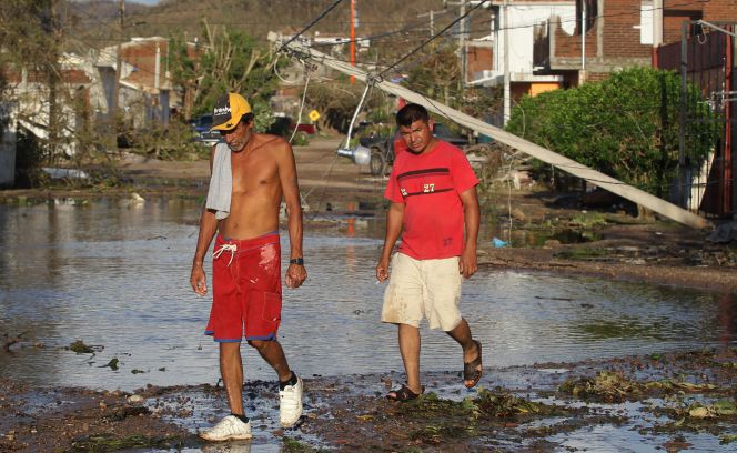 Dos hombres caminan por una calle tras el paso del huracán Patricia en el municipio de Francisco Villa, en el estado mexicano de Jalisco.