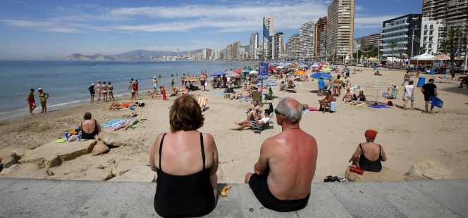 Una pareja de jubilados disfrutan del sol y las altas temperaturas en la playa de Levante en Benidorm, en Alicante.