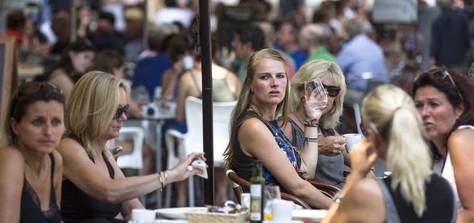 Varios turistas se refrescan, este mediodía, en una terraza junto a La Lonja de Valencia.