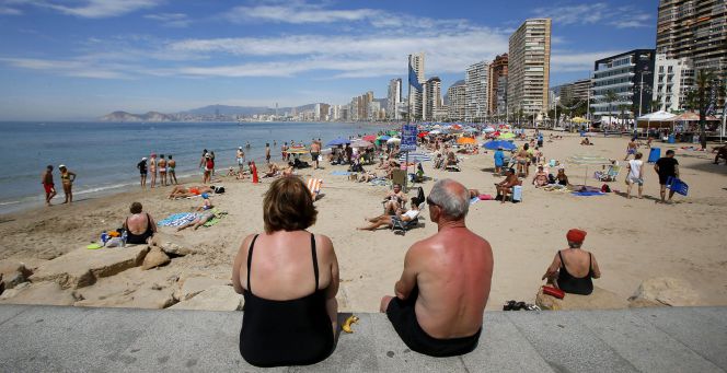 Una pareja de jubilados disfrutan del sol y las altas temperaturas en la playa de Levante en Benidorm, en Alicante.