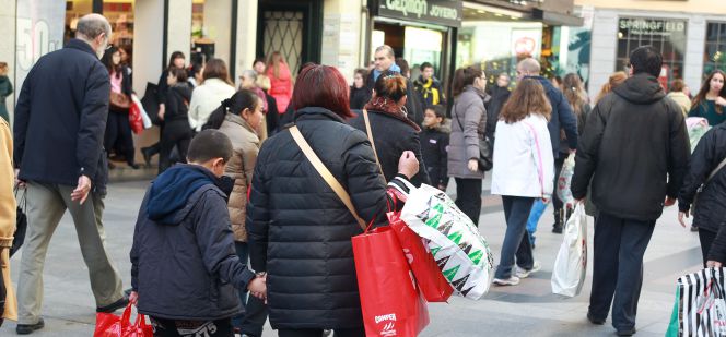 Un grupo de personas pasean con sus compras por la popular calle comercial madrileña de Preciados.