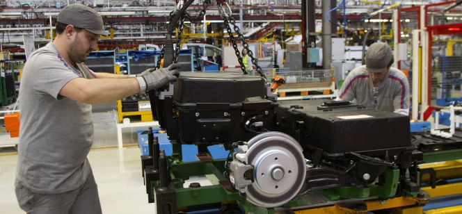 Dos operarios colocan las baterías de la furgoneta eléctrica Citroën Berlingo en la cadena de montaje de la planta de PSA.