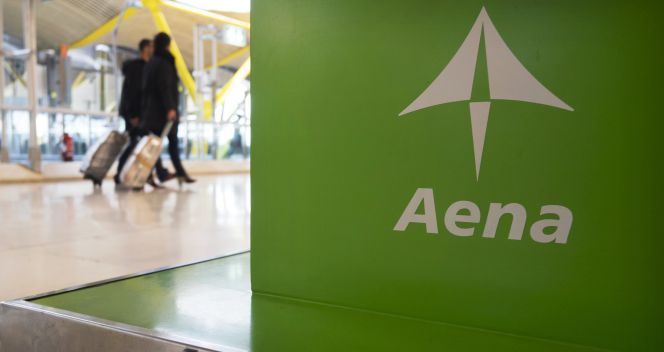 Dos pasajeros pasan ante un expositor de Aena en el aeropuerto madrileño de Barajas. Reuters