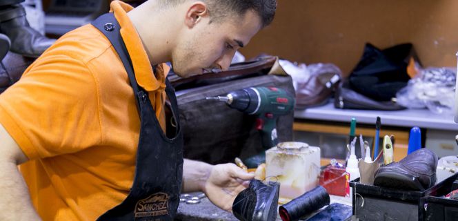 Un empleado de Calzados Sánchez repara un zapato.