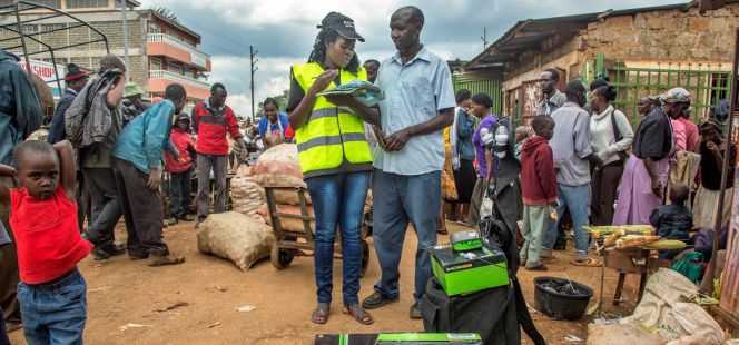 Una representante de ventas de la empresa M-Kopa habla con un usuario del servicio de energía solar en Kenia.