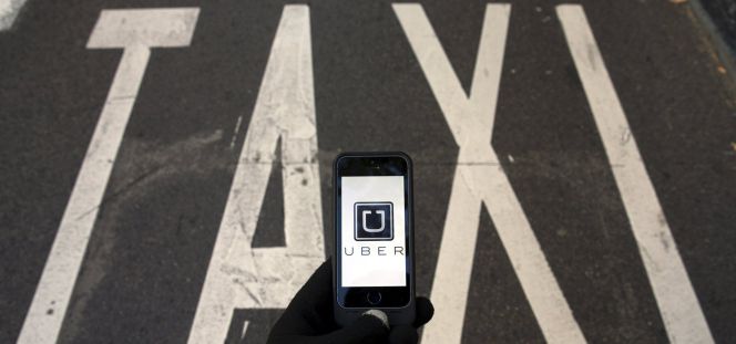 El logo de Uber en un smartphone junto a un rótulo de taxi.
