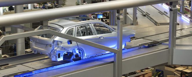 La carrocería de un coche es transportada por una línea de montaje sobre las cabezas de los empleados en la planta que la fabricante de automóviles BMW tiene en Leipzig (Alemania).