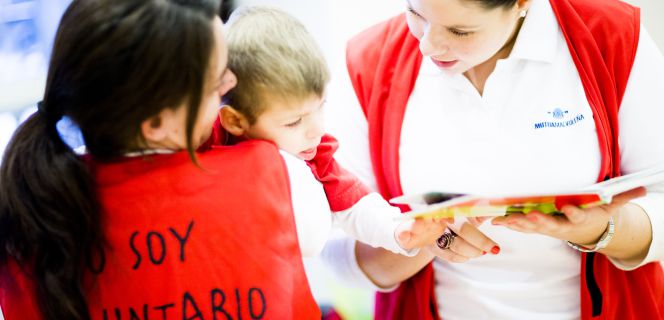 Dos voluntarias de una organización colaboran en una actividad con menores.