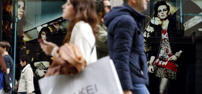 Varias personas pasan con bolsas de compras ante una de las tiendas de la céntrica calle Preciados de Madrid.