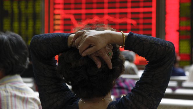 Una mujer comprueba la evolución de la bolsa de Shangái en Pekín (China).