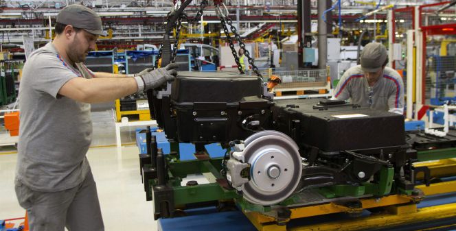 Dos operarios colocan las baterías de la furgoneta eléctrica Citroën Berlingo en la cadena de montaje de la planta de PSA.